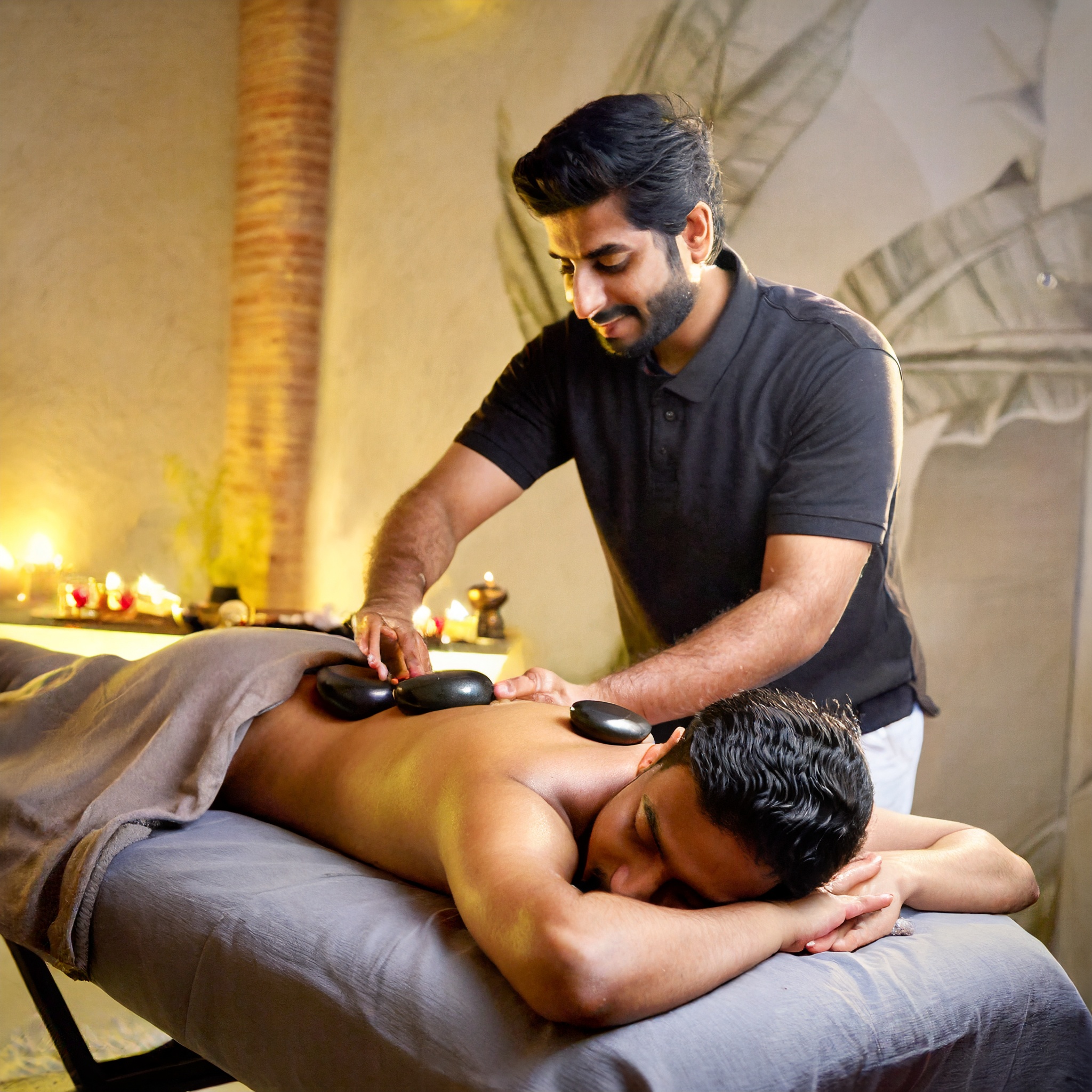 A male masseur giving a Soothing Hot Stone Massage to male customer
